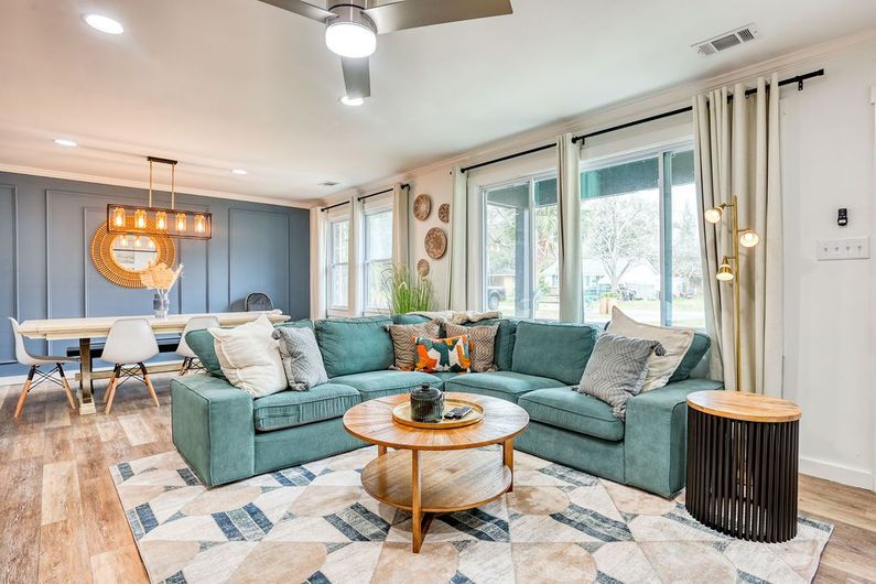 Spacious living room with teal sectional sofa, wood coffee table, and dining area with blue accent wall.