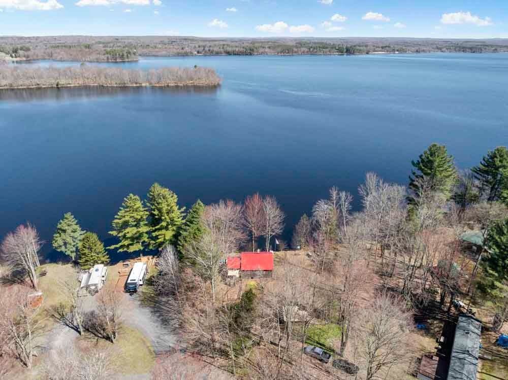 An aerial view of a house on the shore of a lake surrounded by trees.