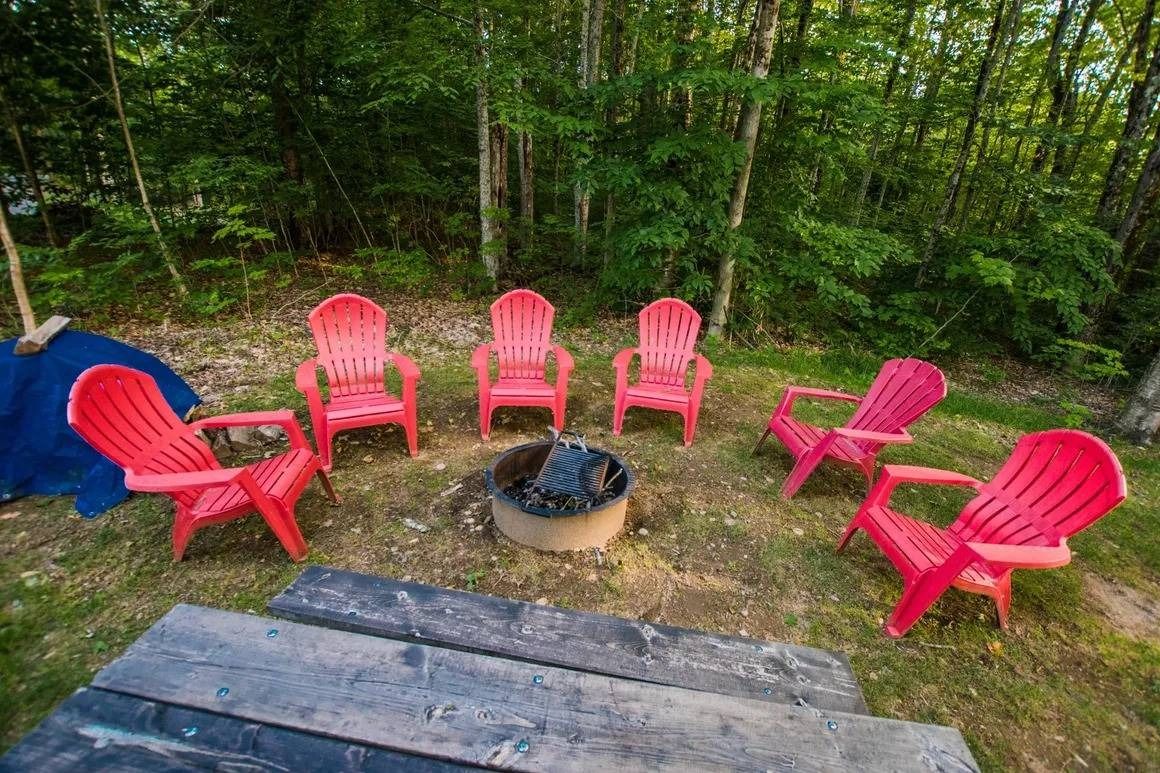 A group of red chairs are sitting around a fire pit.