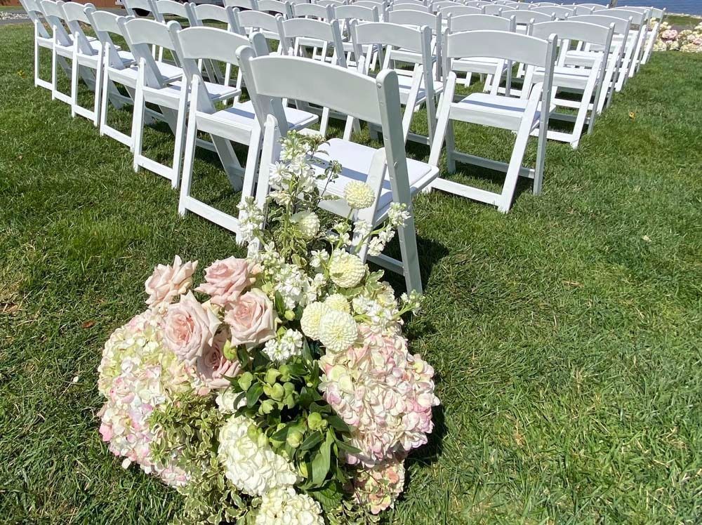 A row of white folding chairs sitting on top of a lush green field.