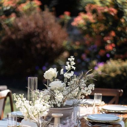 A table with plates , glasses , vases and flowers on it.