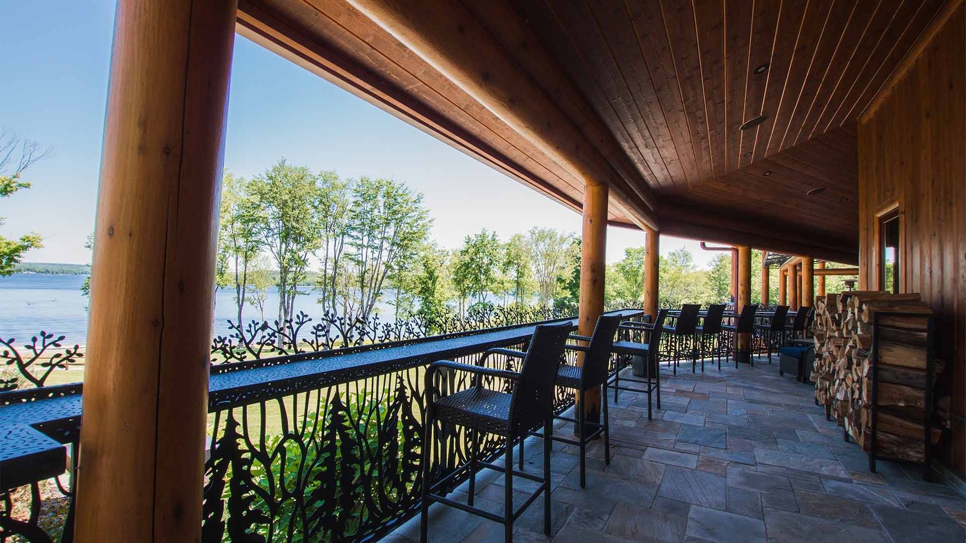 A large porch with a view of a lake and trees.