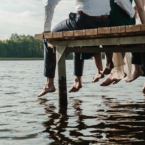 A group of people sitting on a wooden dock overlooking a lake