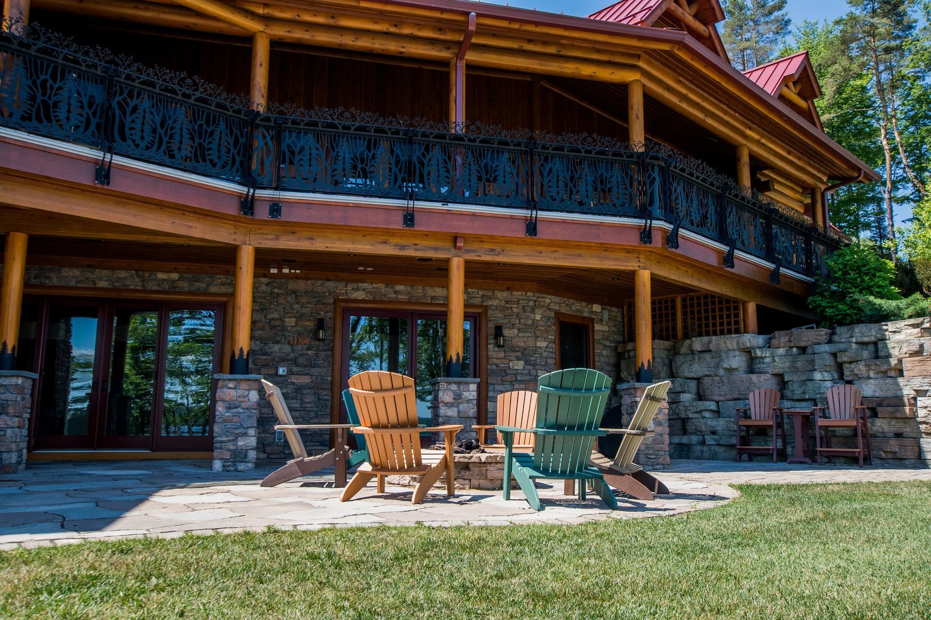 A large log cabin with a patio and chairs in front of it.