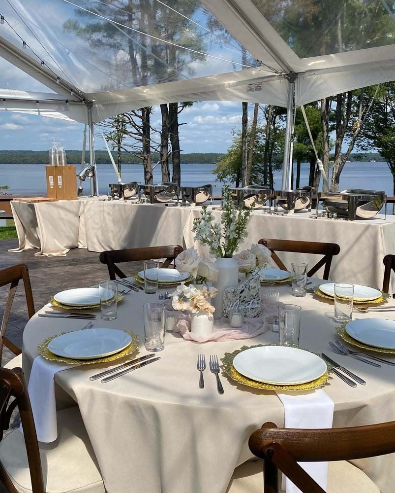 A table set for a wedding reception under a clear tent.