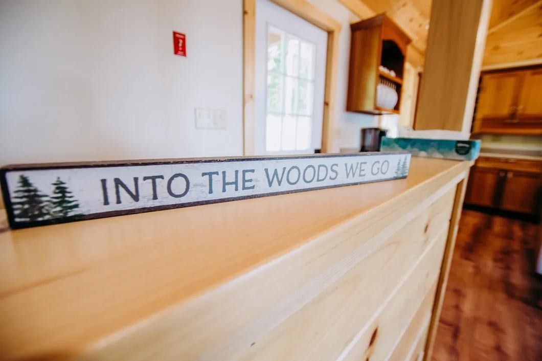 A sign that says `` into the woods we go '' is on a wooden counter.