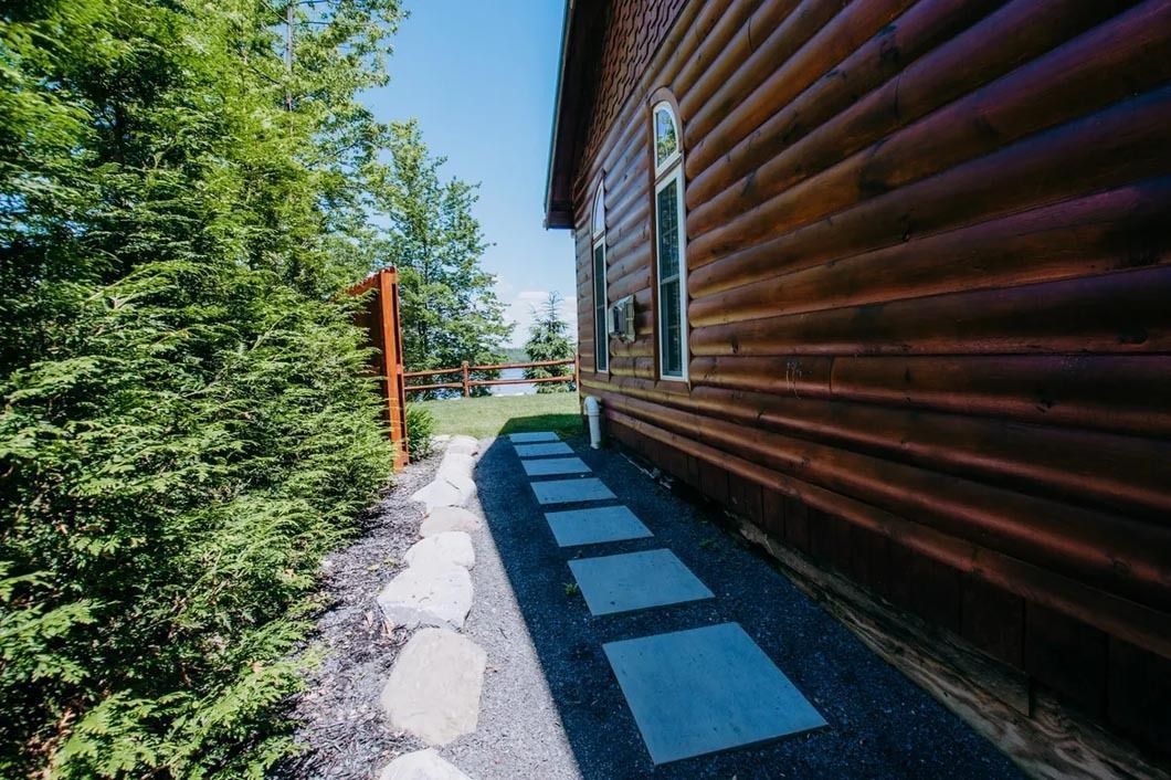 There is a walkway leading to the side of a log cabin.