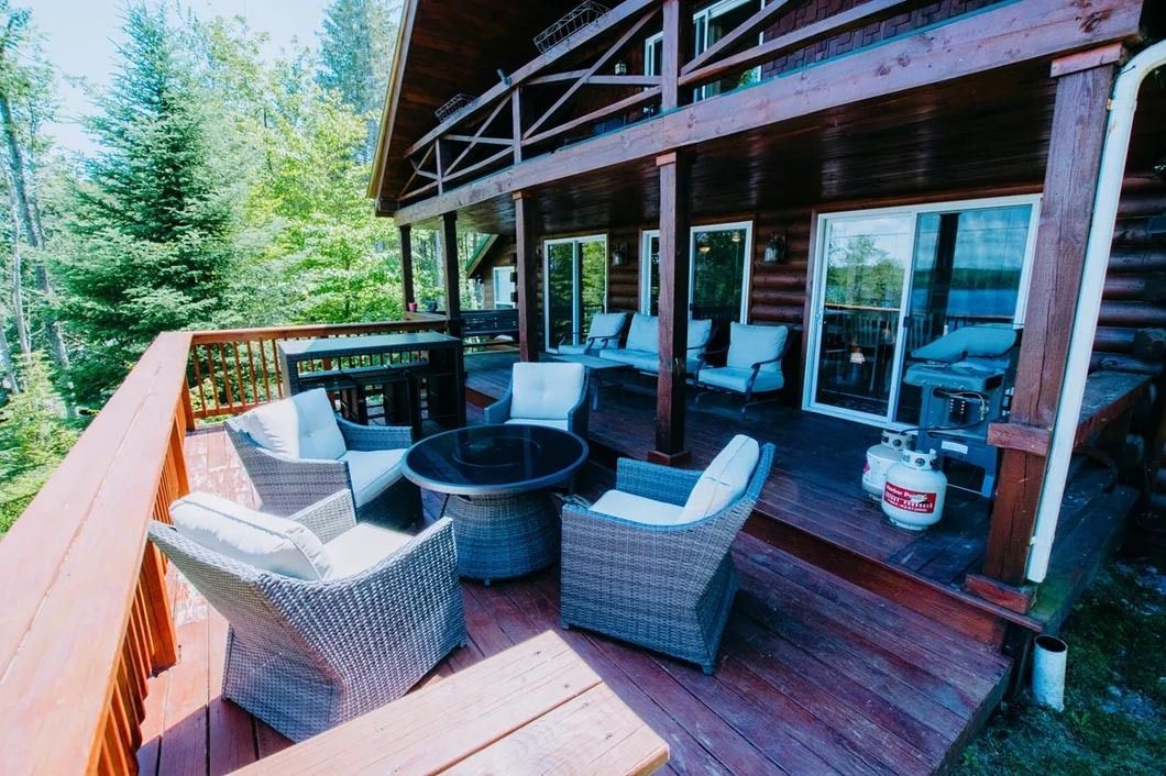 A large wooden deck with wicker furniture and a fire pit.