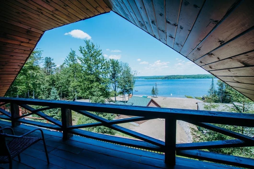 A balcony with a view of a lake and trees.