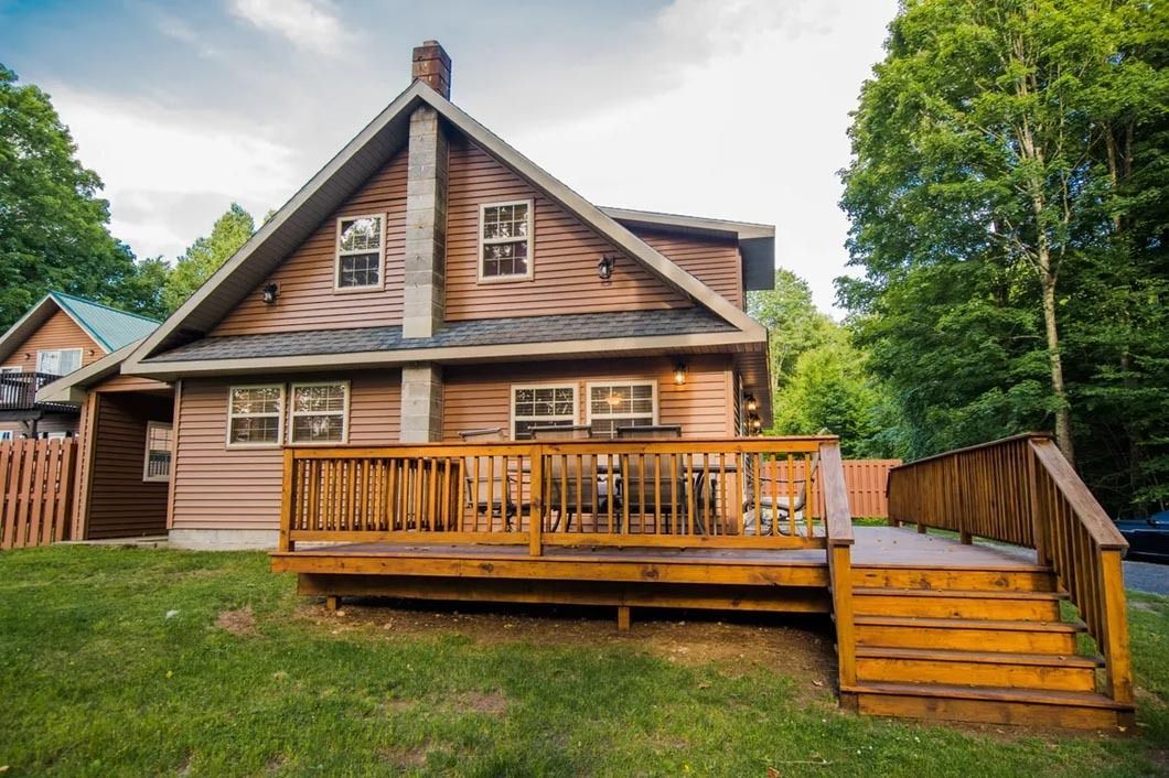 A large wooden house with a large wooden deck in front of it.