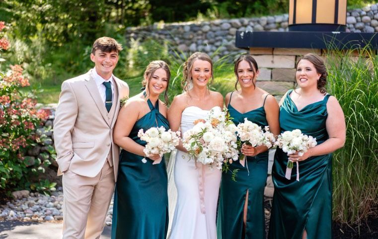 The bride and groom are posing for a picture with their bridesmaids.