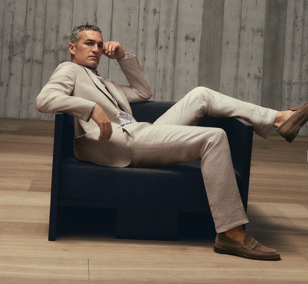 A man in a suit and bow tie is standing next to a white car.
