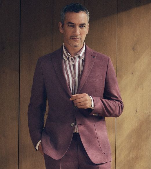 A bride and groom sit on a couch in the grass