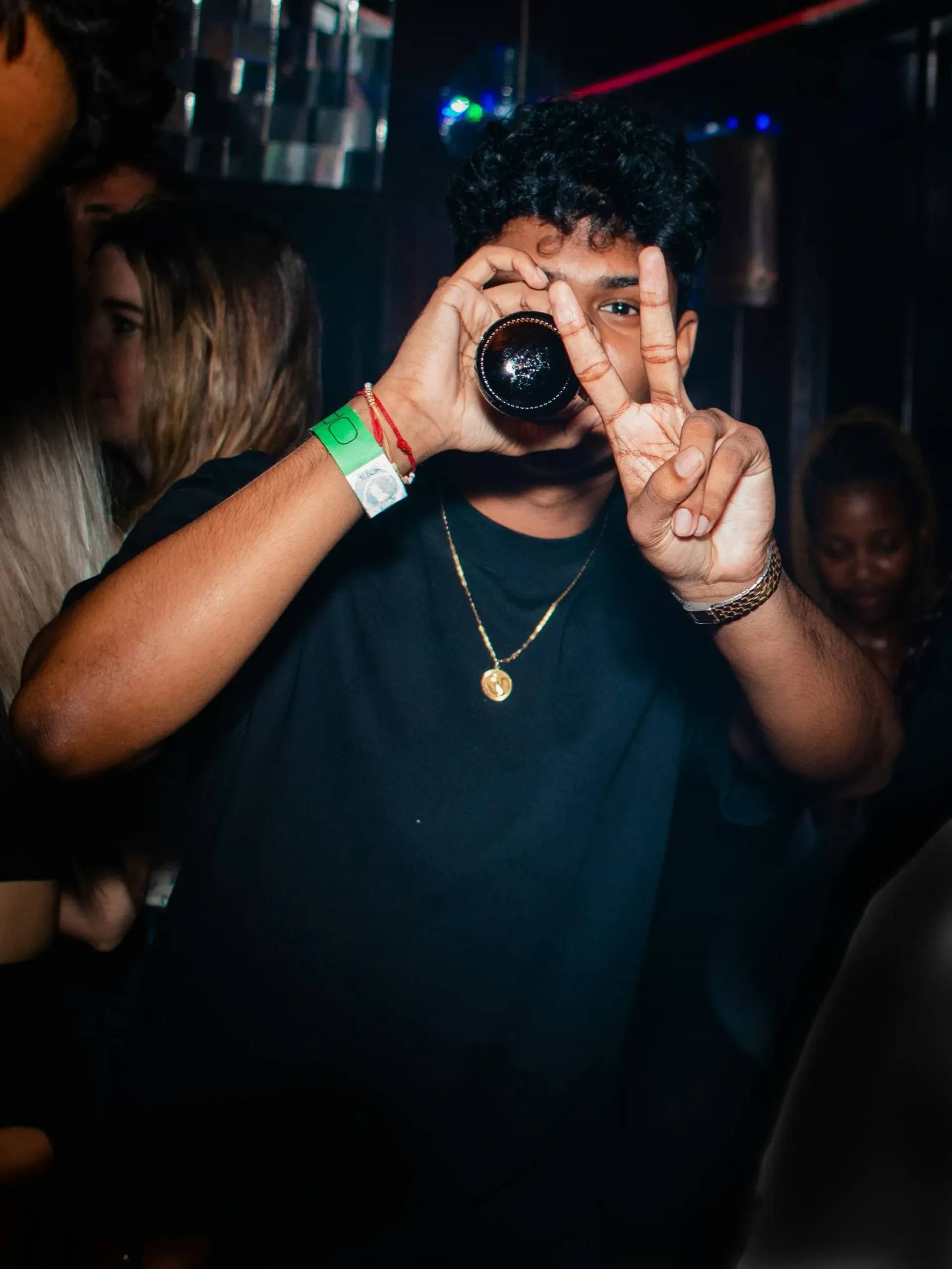 Man drinking alcohol covering his fave with peace hand gesture.
