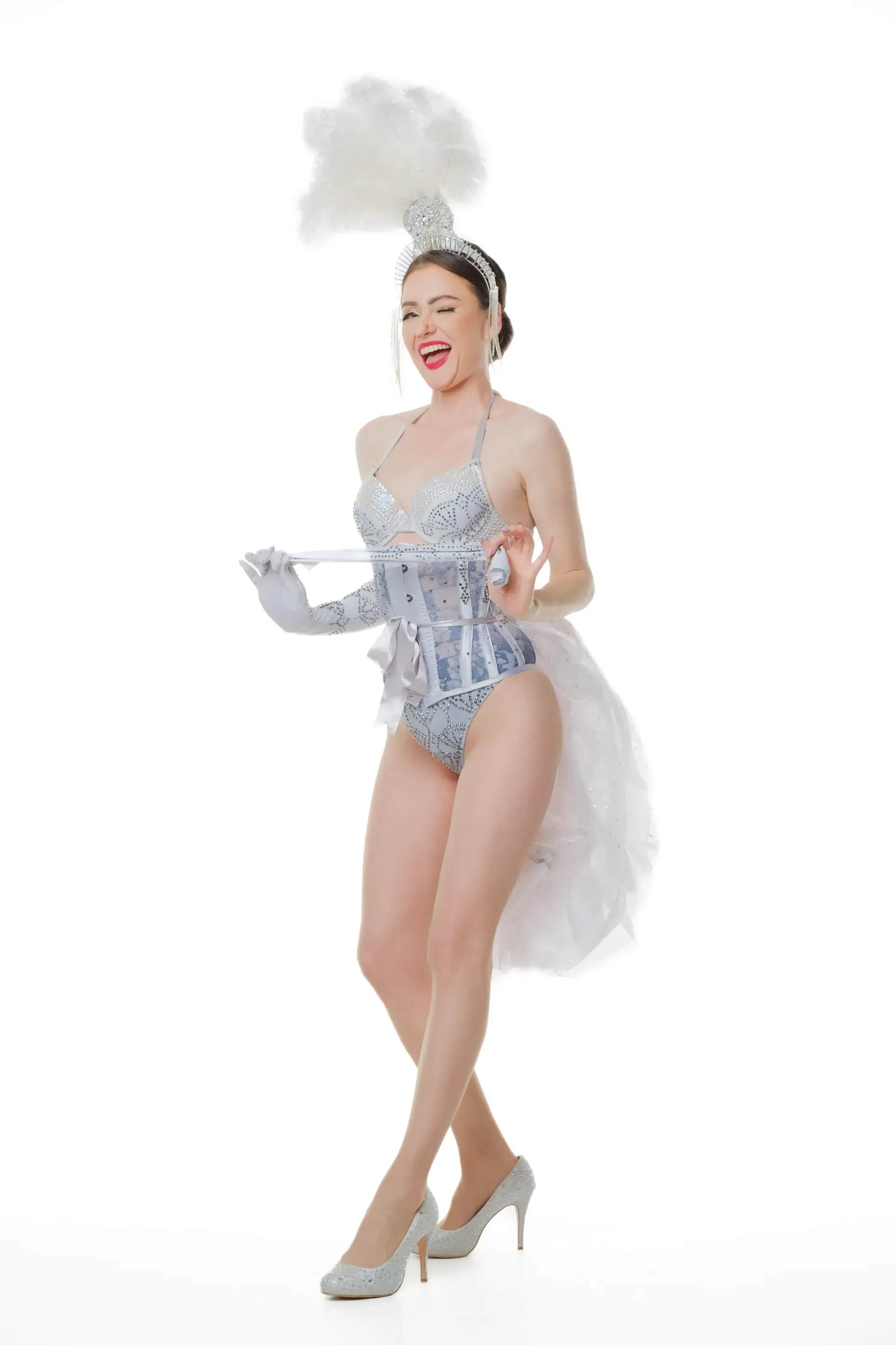 Burlesque performer in sparkly silver costume with feather headpiece and tail, holding glove.