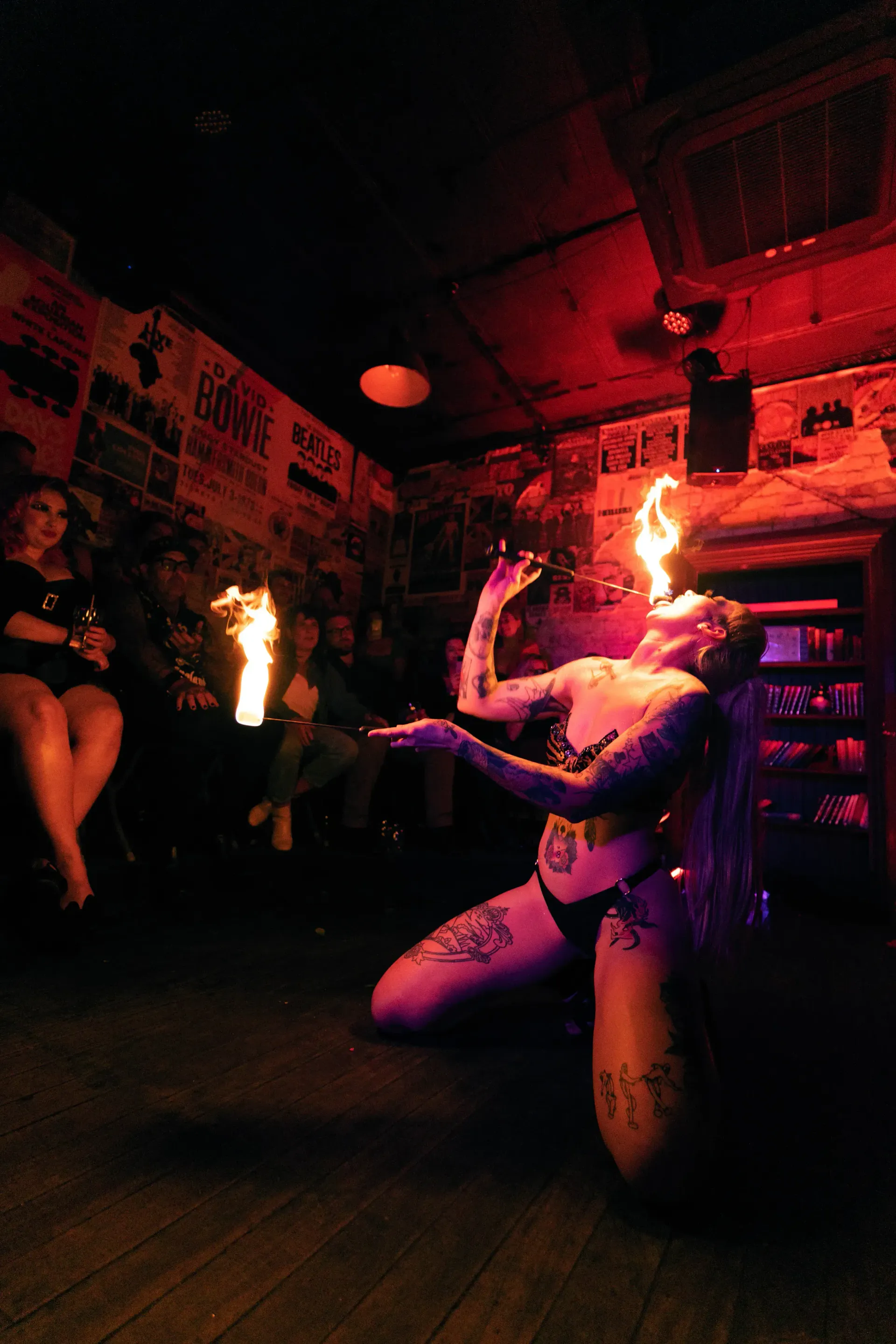 Fire dancer in black lingerie costume eating fire in front of audience.