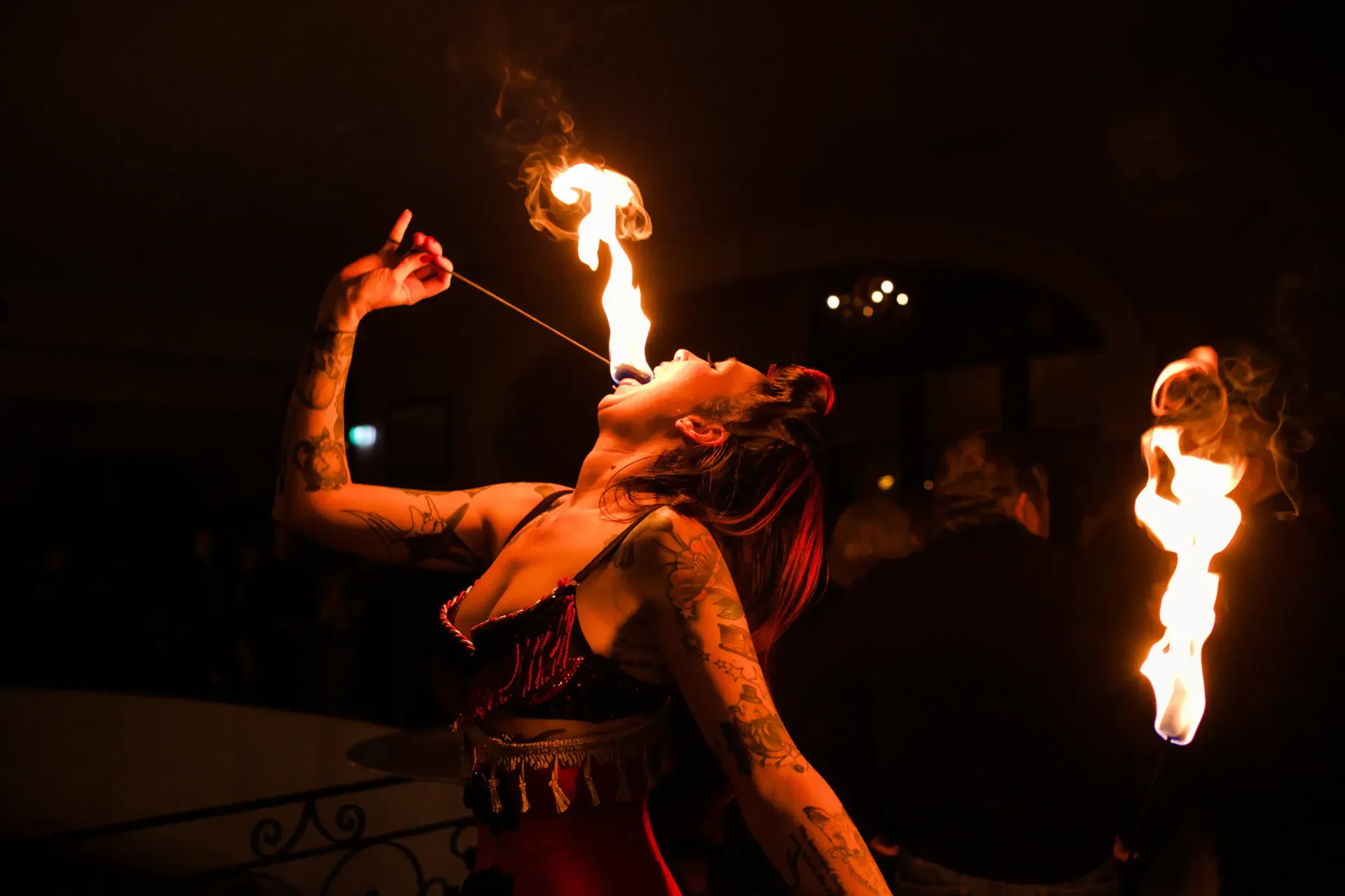 Fire dancer in a dark setting, flames emanating from her mouth and hands.