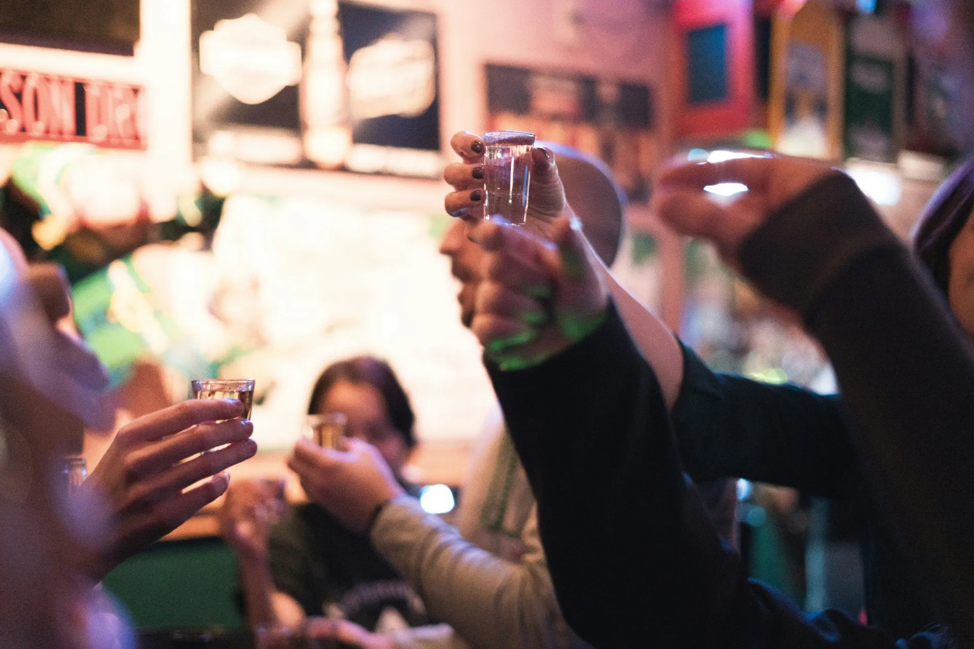 Group of people at a party cheering with their shot glasses.