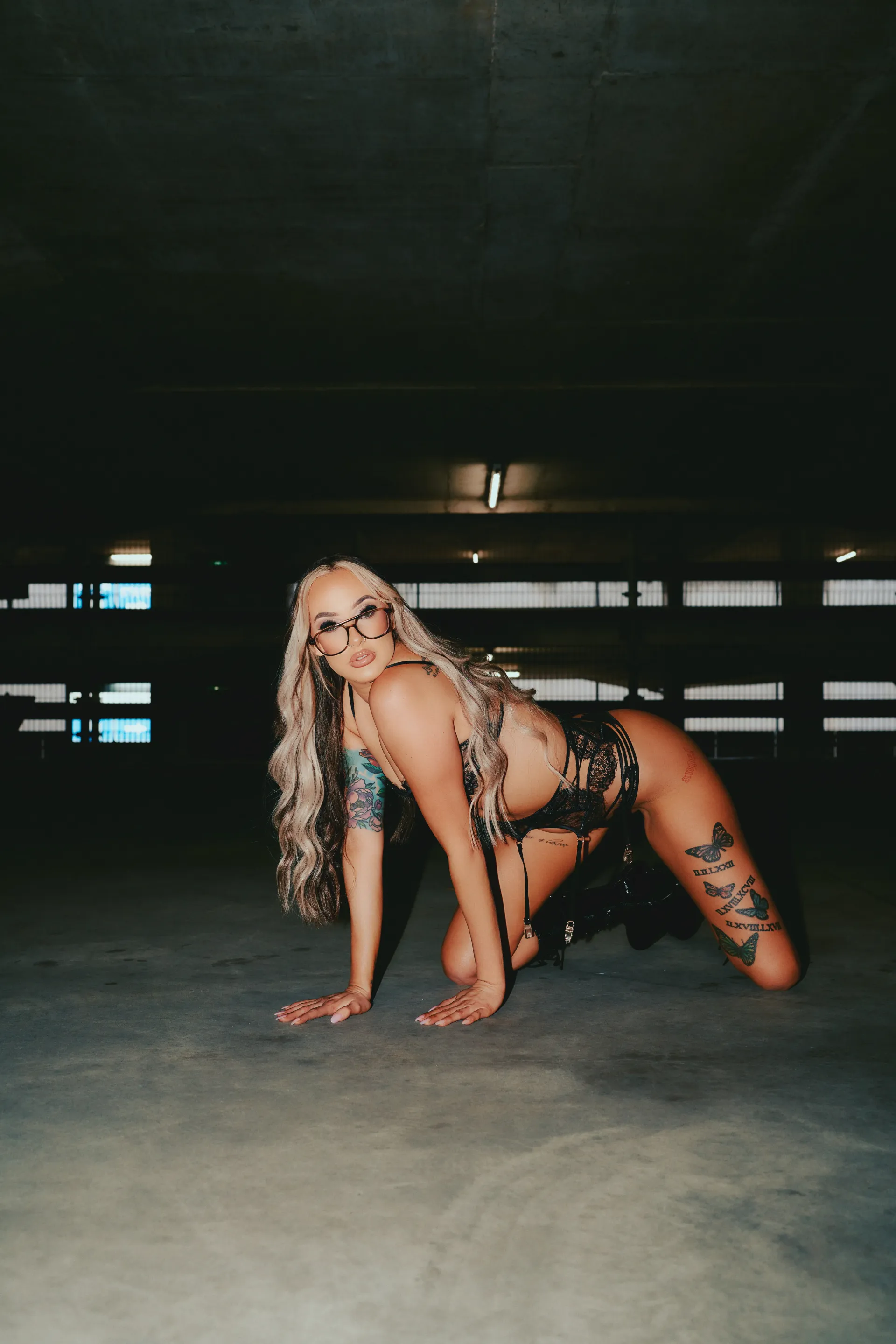 Stripper with wavy hair posing in black outfit against dark background