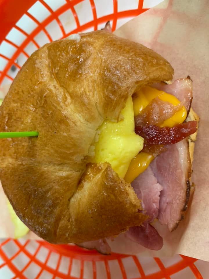 Croissant sandwich with ham, cheese, and pineapple, held together with a green toothpick.