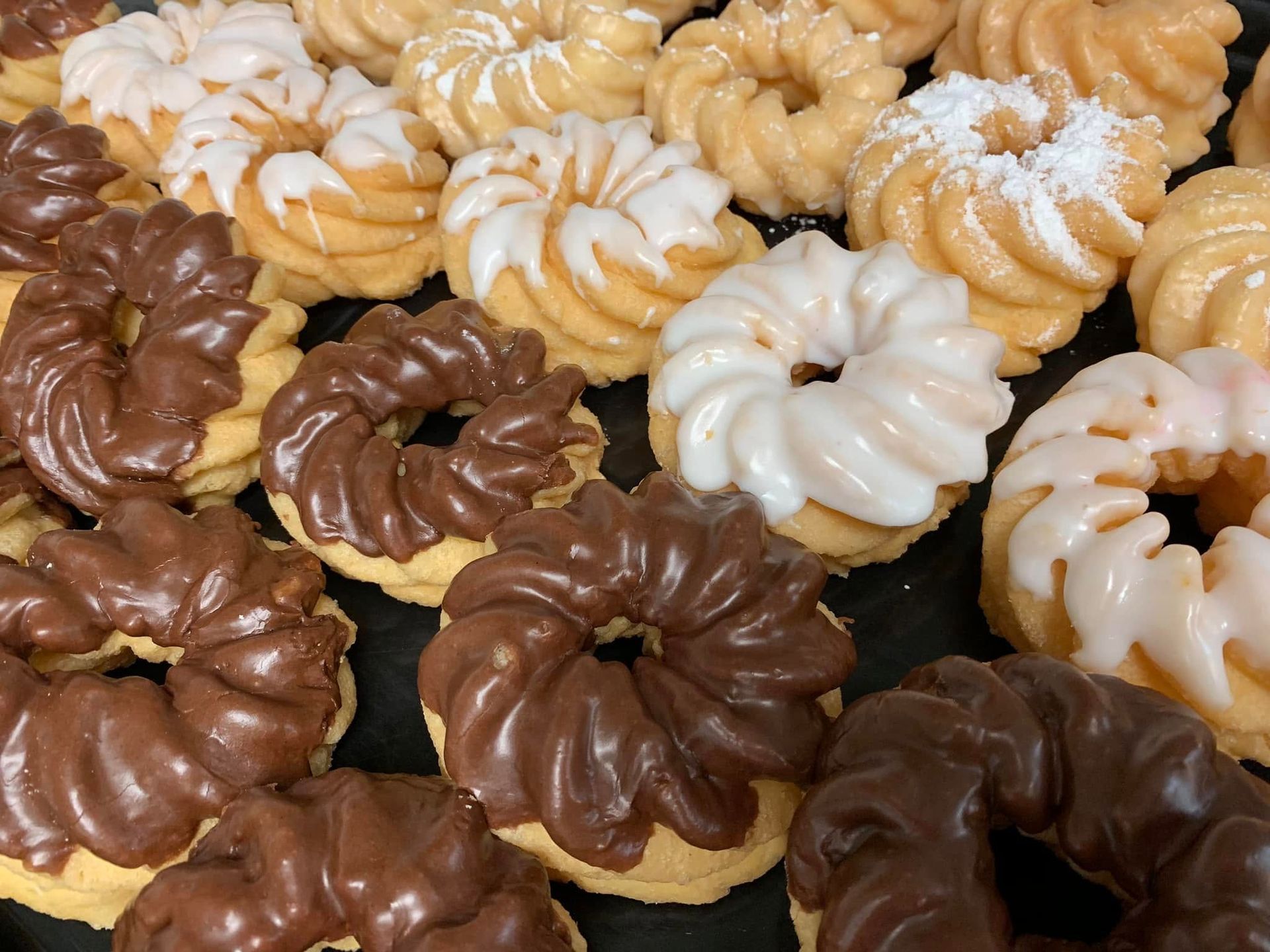 Close-up of a tray of cruller donuts with chocolate and vanilla frosting.