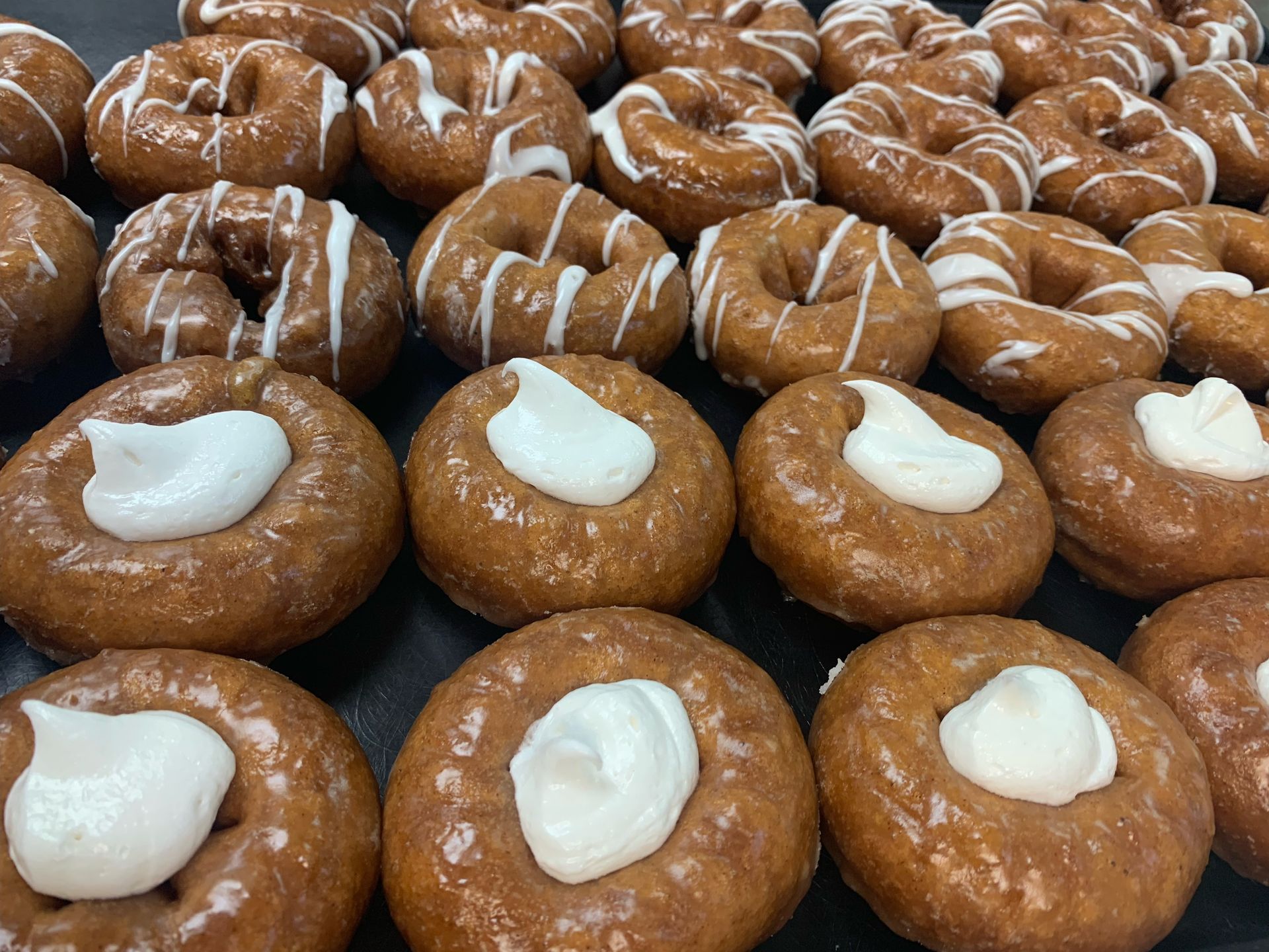 Donuts: glazed with white frosting drizzled on top or topped with a dollop of cream.