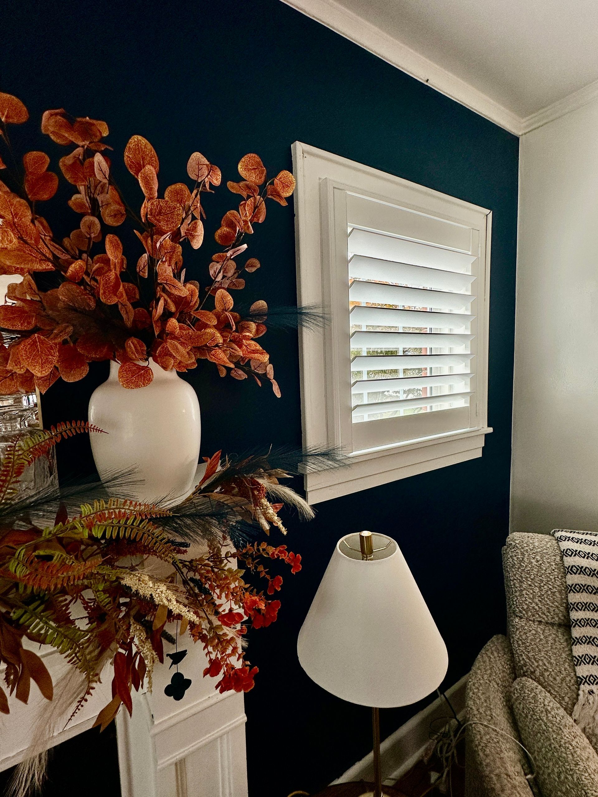 plantation shutter in a room with fall foliage and navy walls 