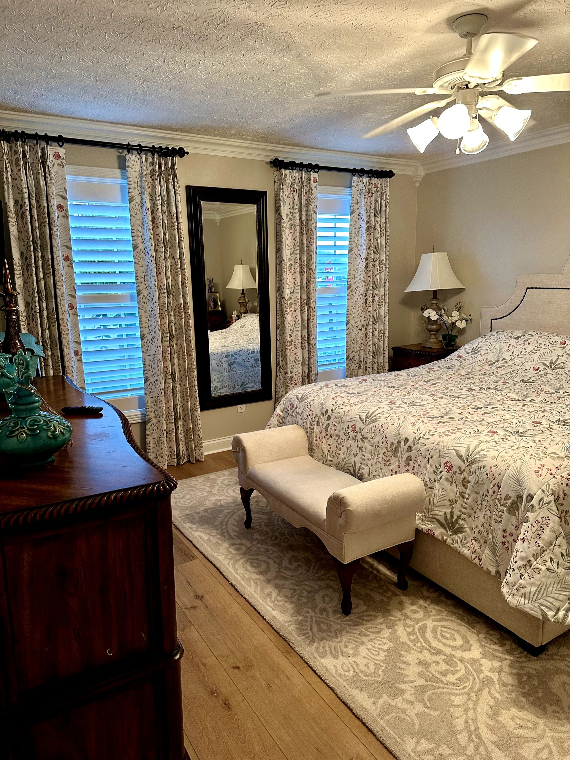 Bedroom with two beds, beige walls, tan curtains, and natural light from windows.