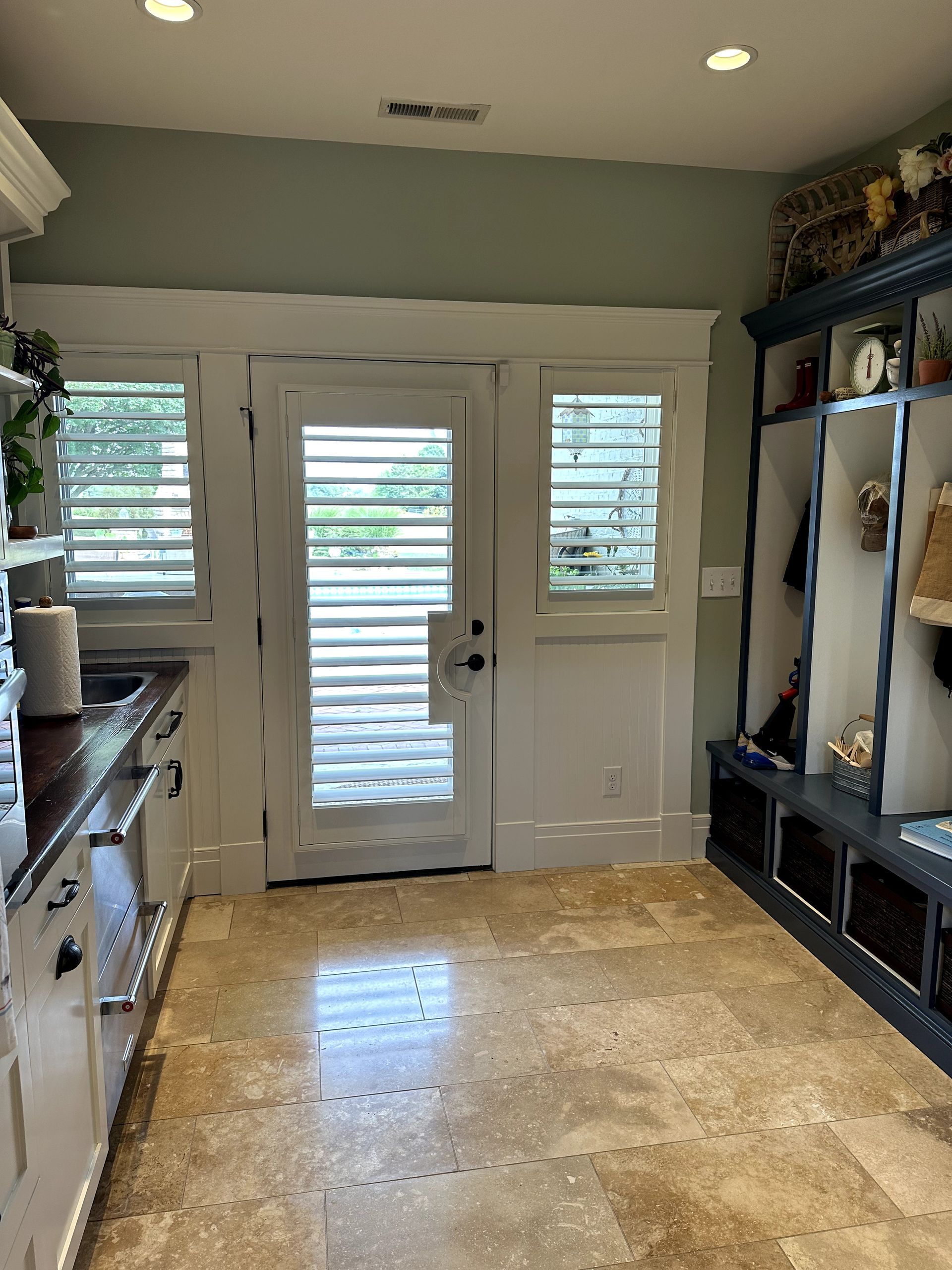 Mudroom with white doors, blue built-ins, and tan tile floor.