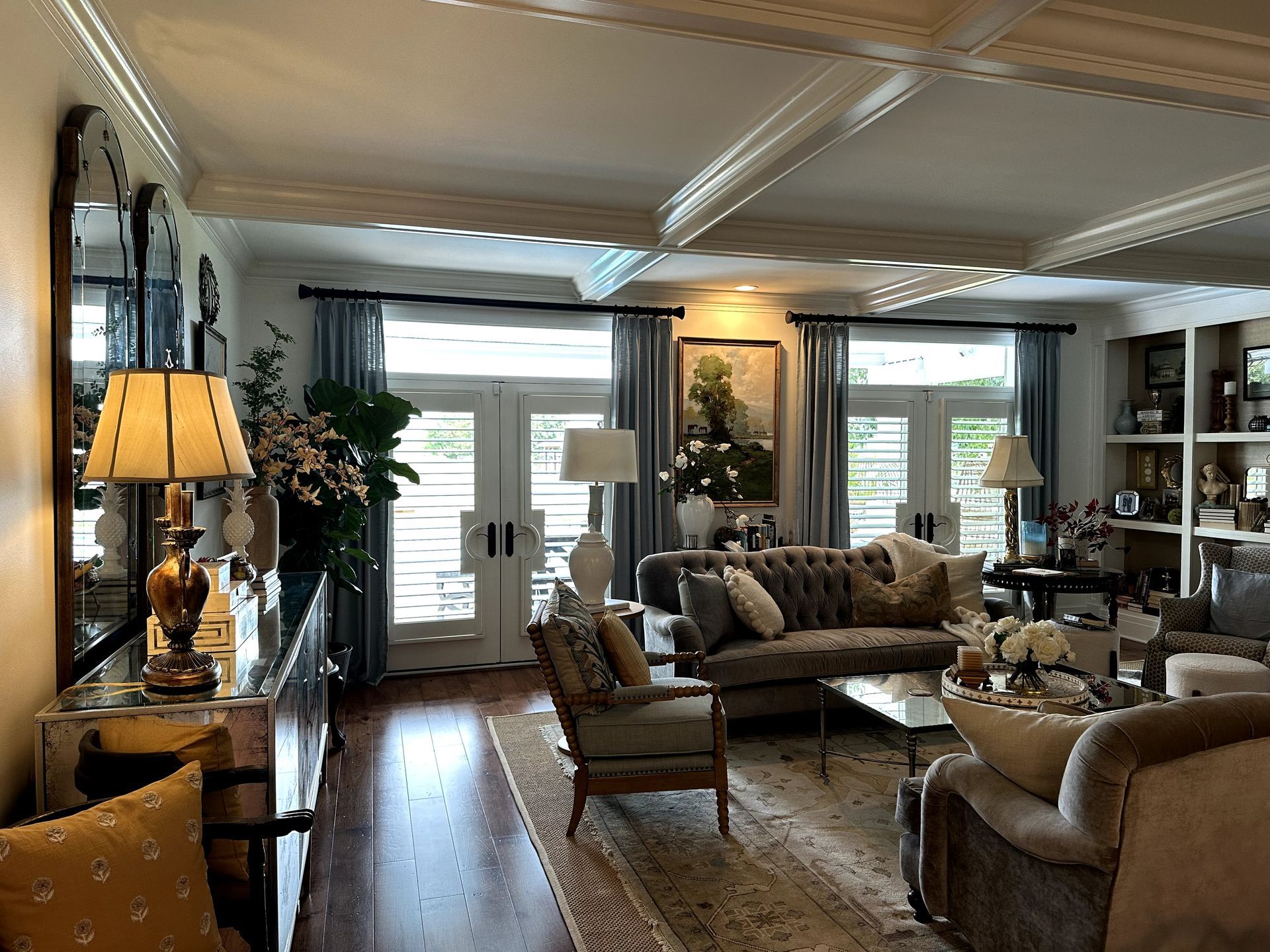 Elegant living room with mirrored furniture, a tufted sofa, and blue curtains.