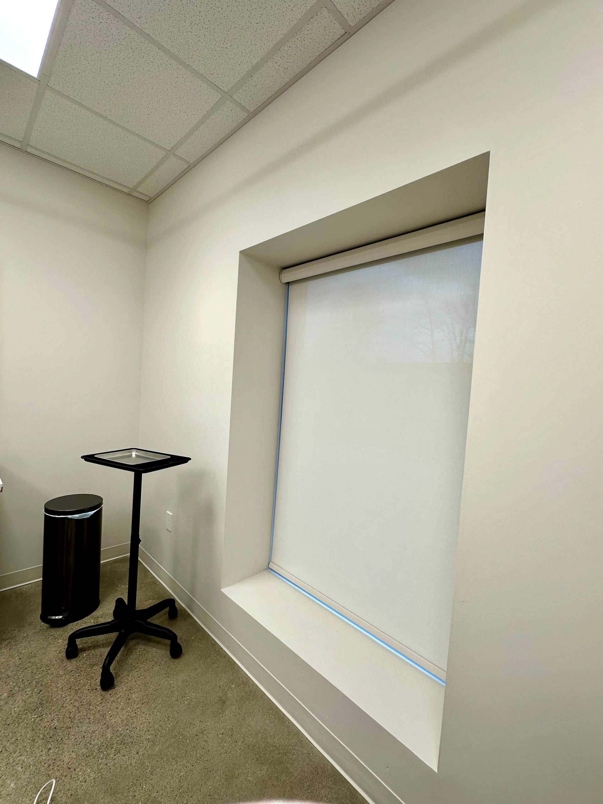 A small, white-walled office room with a window and a small table.