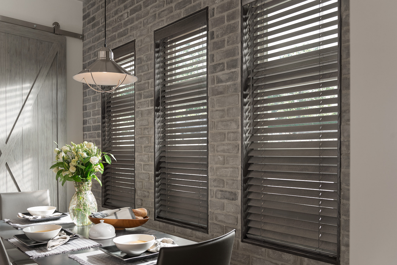 Dining room with wooden blinds on brick wall, table set for meal.