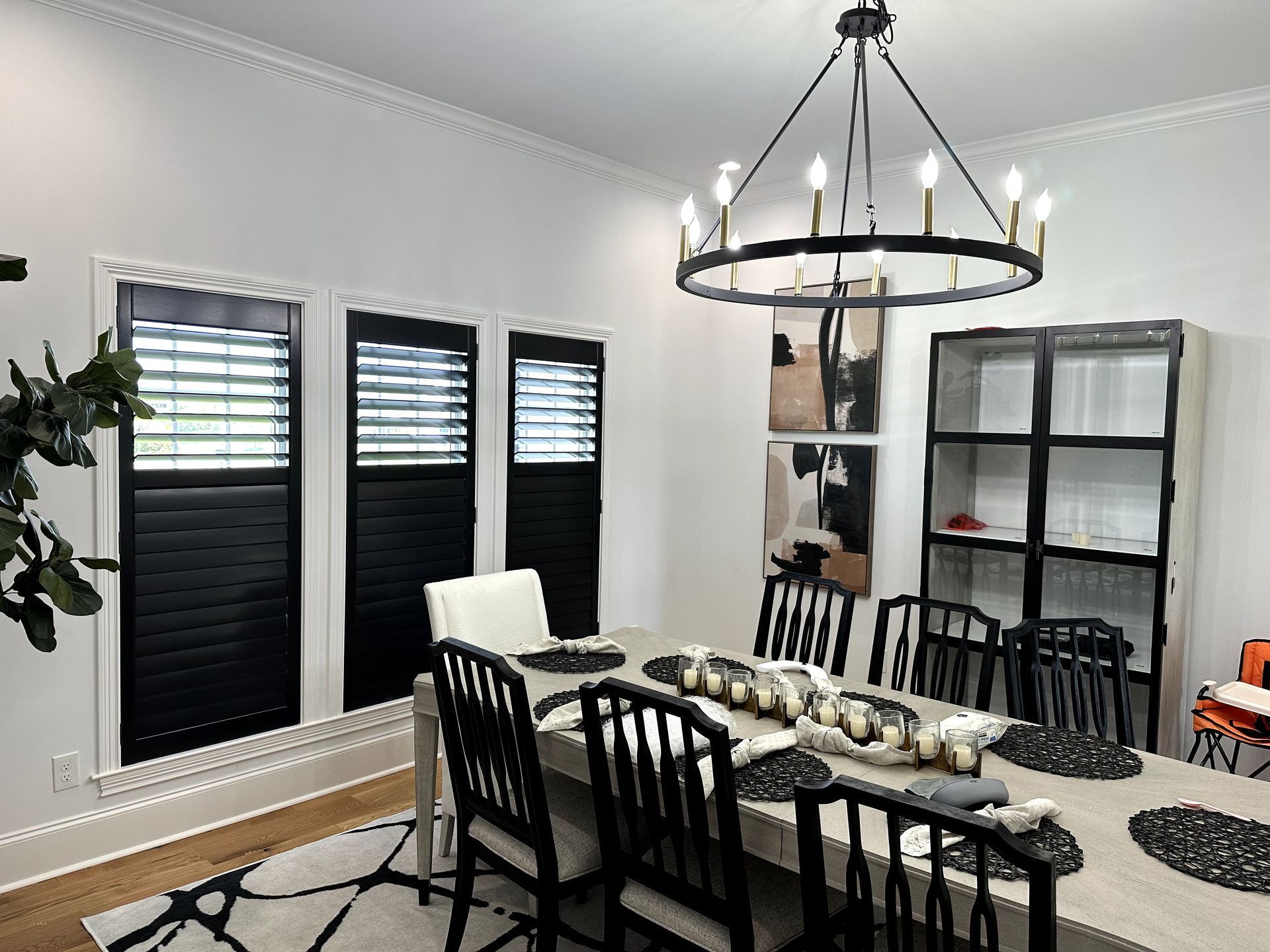 Dining room with rectangle table, black wood shutters, black chairs, round chandelier