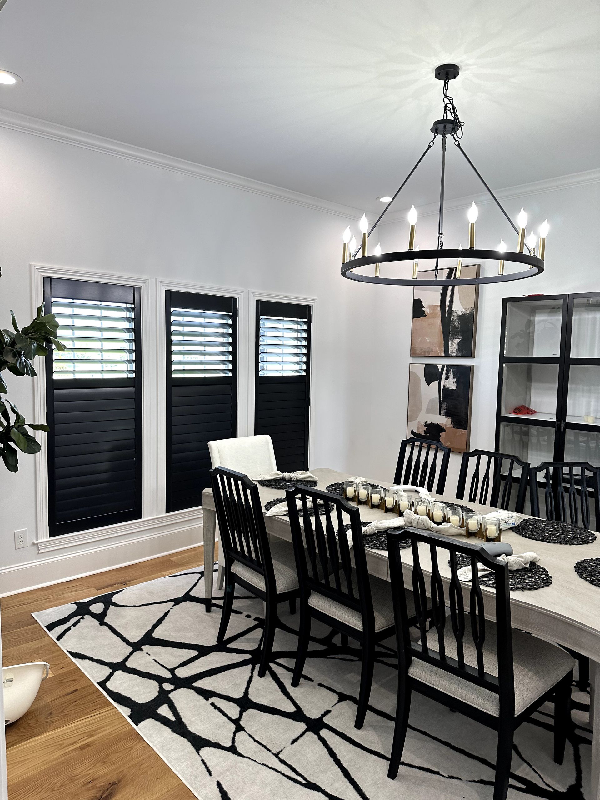 Elegant dining room with black and white decor, including a chandelier over a long table with eight black chairs.