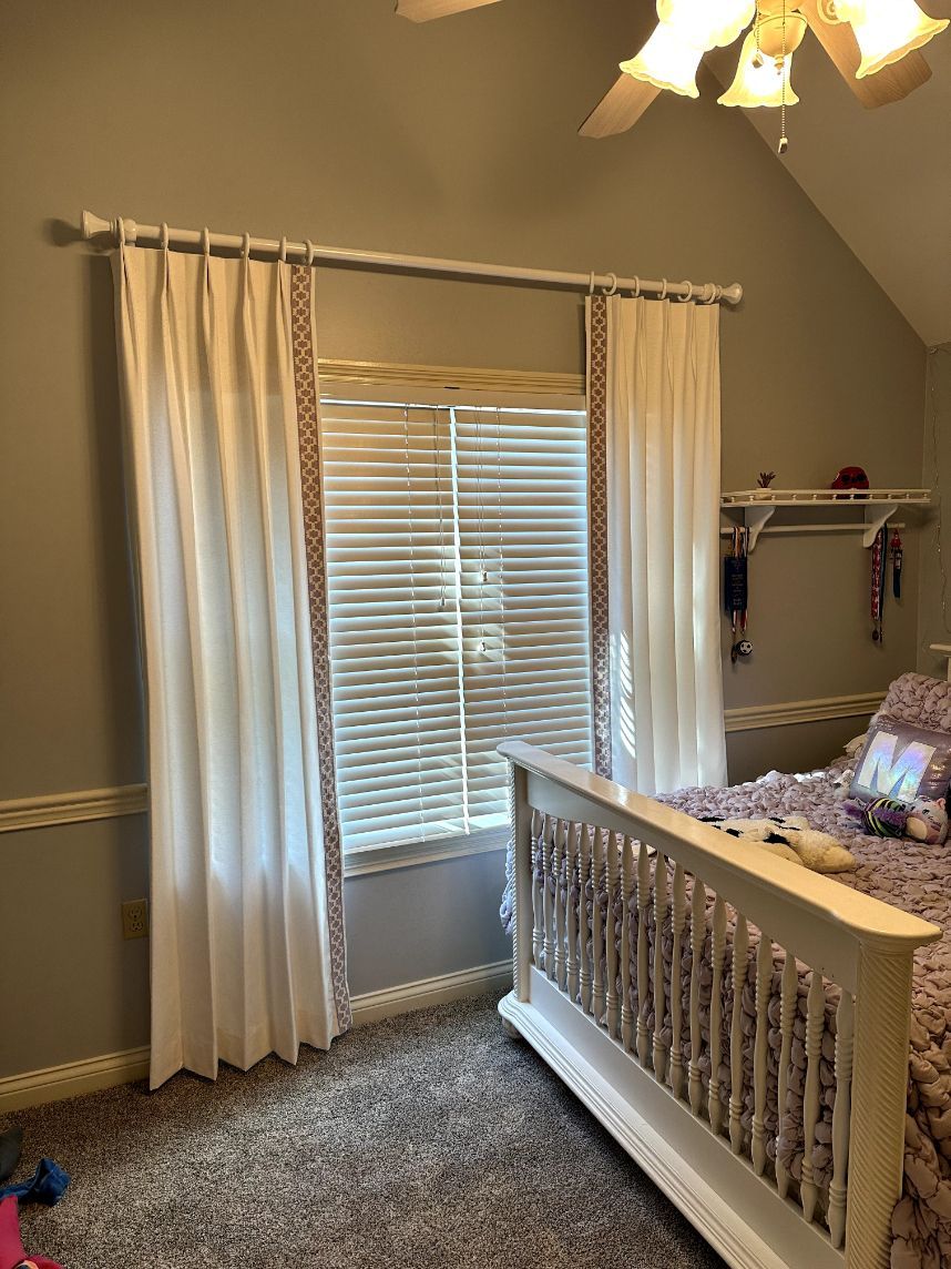 A cheerful bedroom has real wood blinds on the windows with drapery - window fashions on wheels, ky
