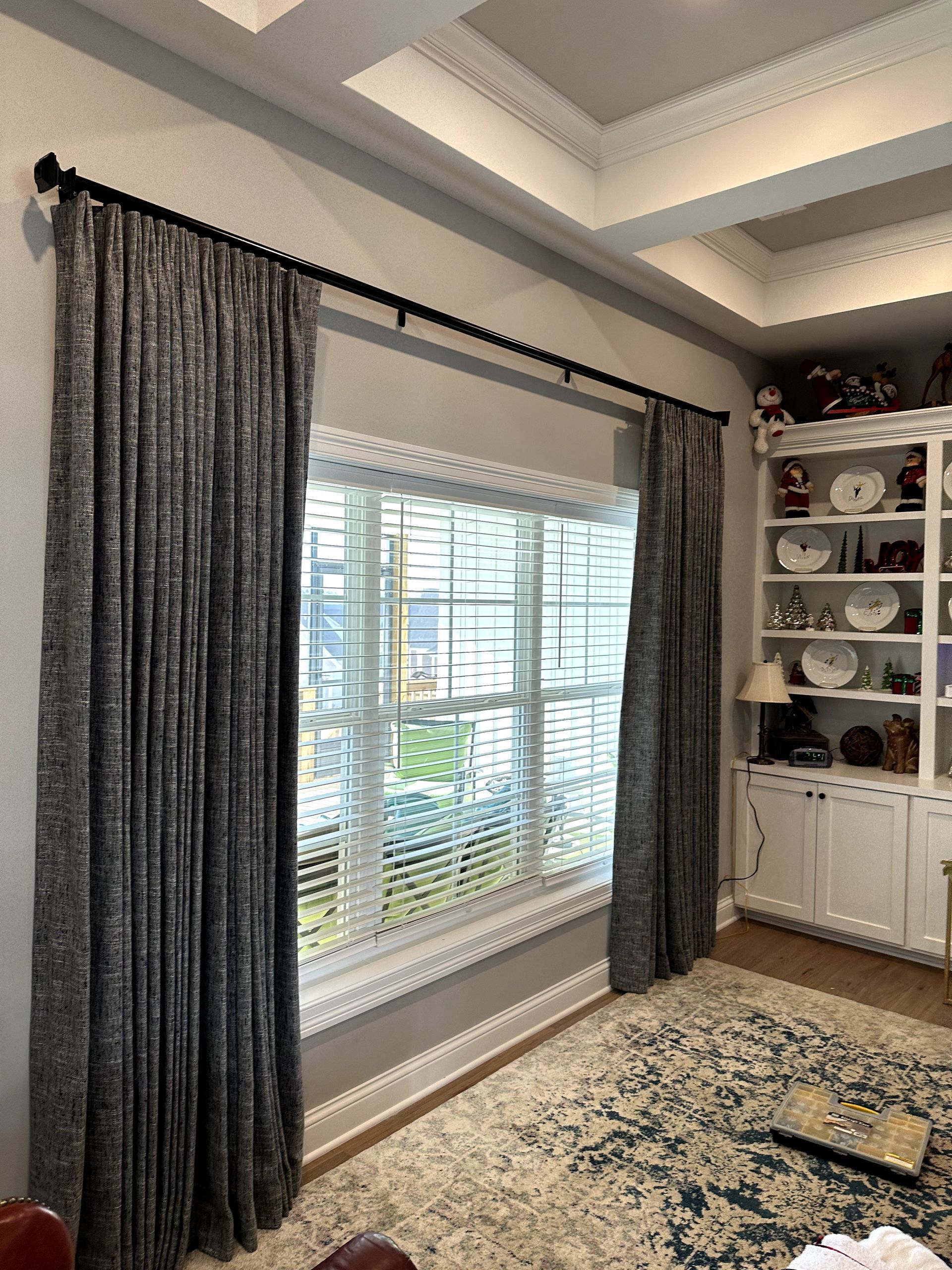 Window with dark gray patterned drapes and blinds. A built-in bookshelf is to the right.