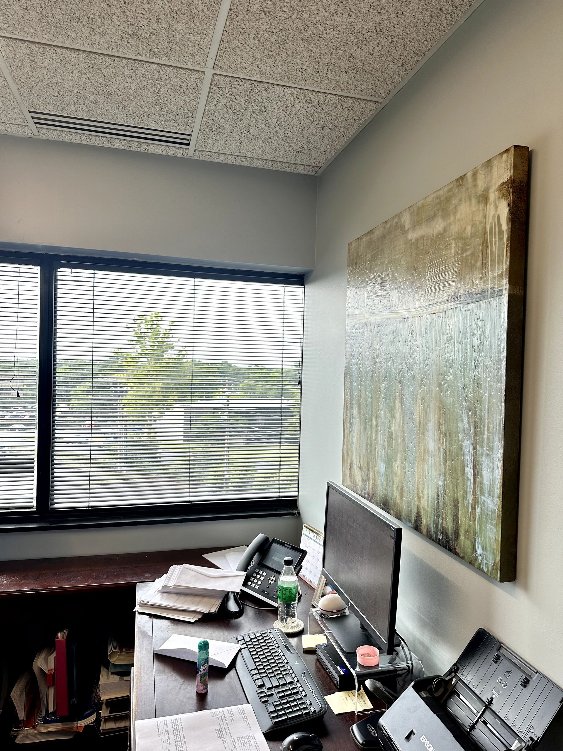 Office interior with a desk, window, art, and computer.