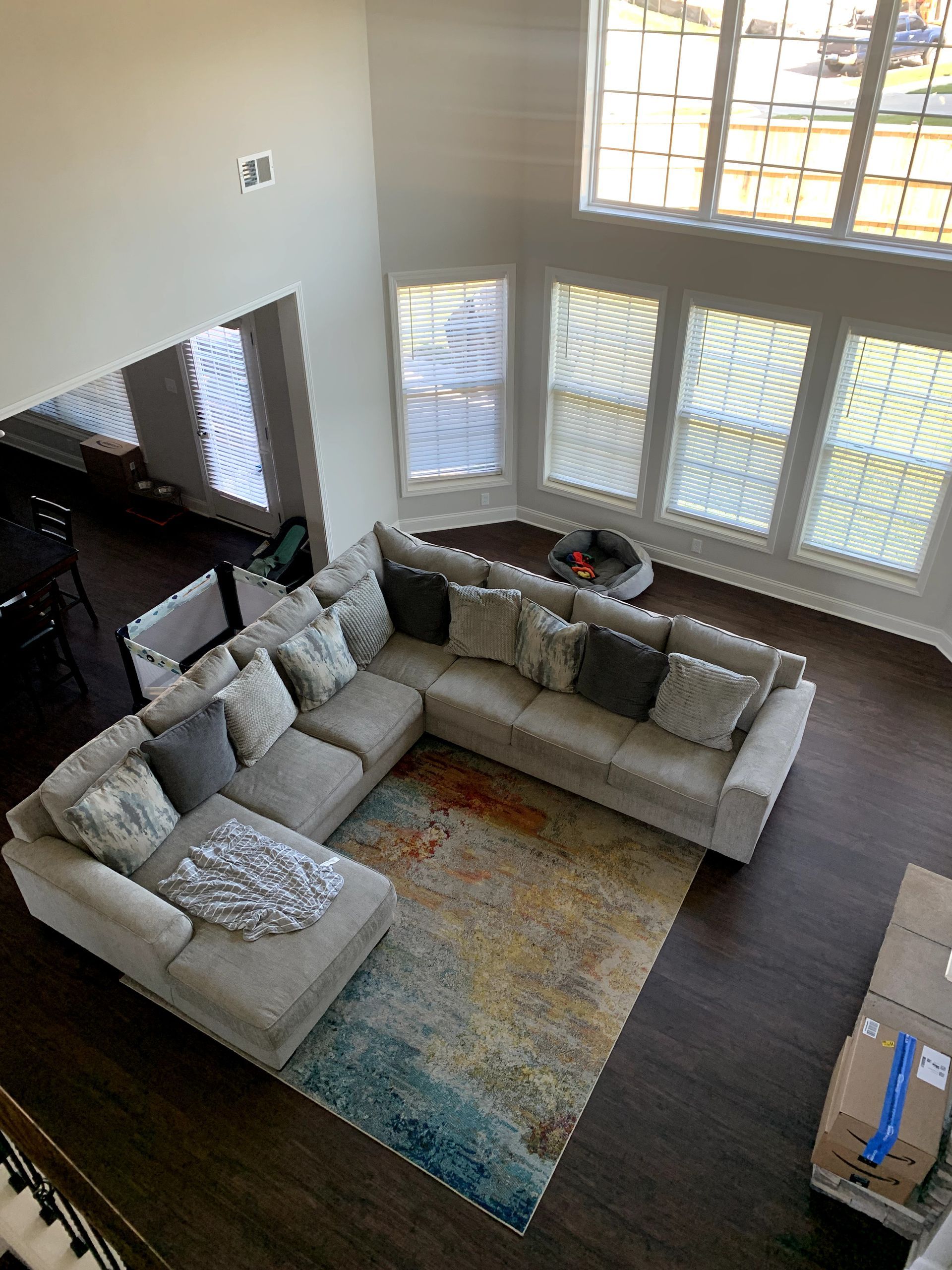 High-angle view of a living room with a sectional sofa, colorful rug, and large windows.