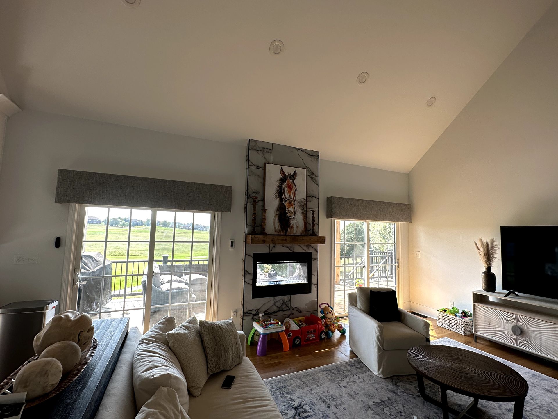 Living room with a fireplace, painting of a horse, and sliding glass doors.