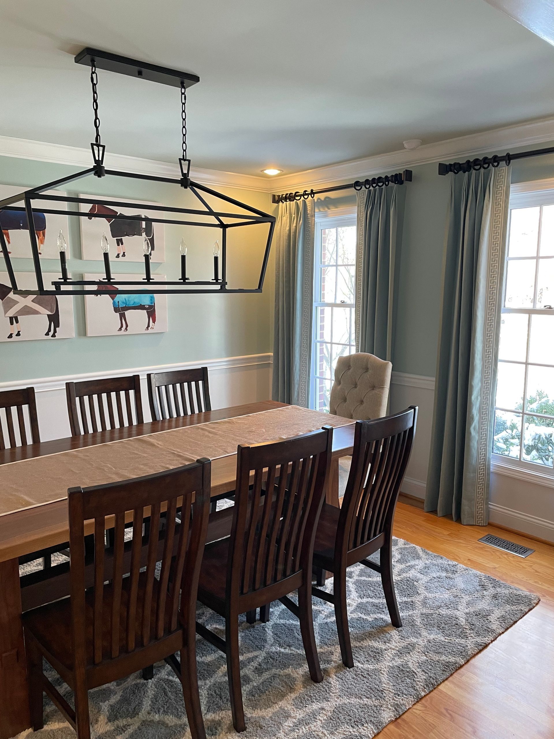 Dining room with long wooden table, chairs, and a rectangular chandelier.
