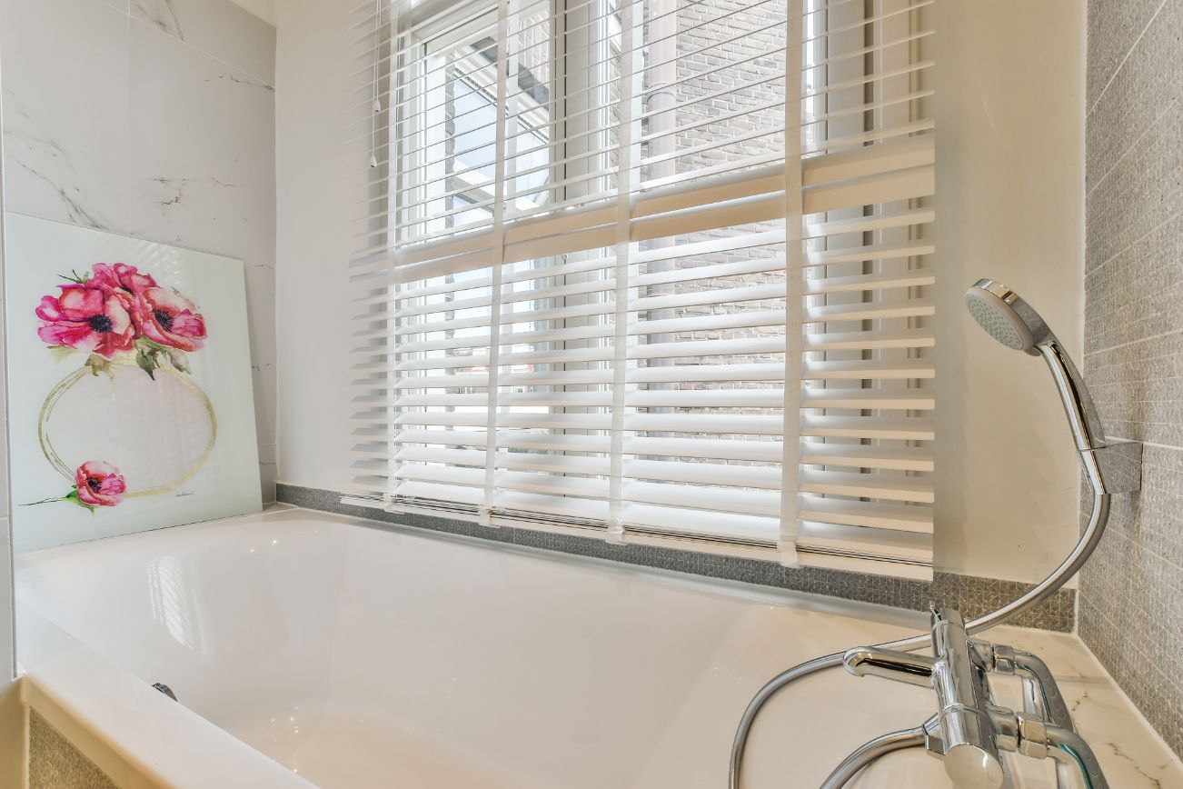 Large white tub in front of a window with whit faux blinds-window fashions on wheels