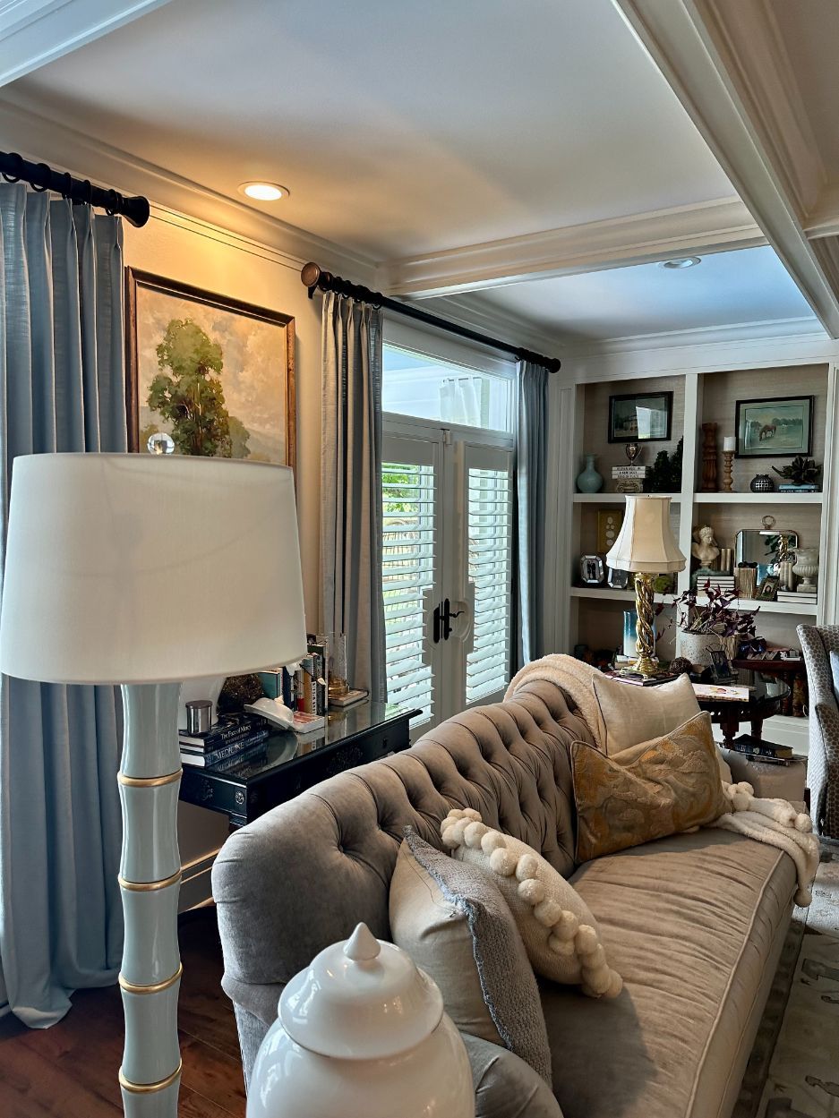 Elegant living room with tufted sofa, floor lamp, and built-in shelving by a bright window