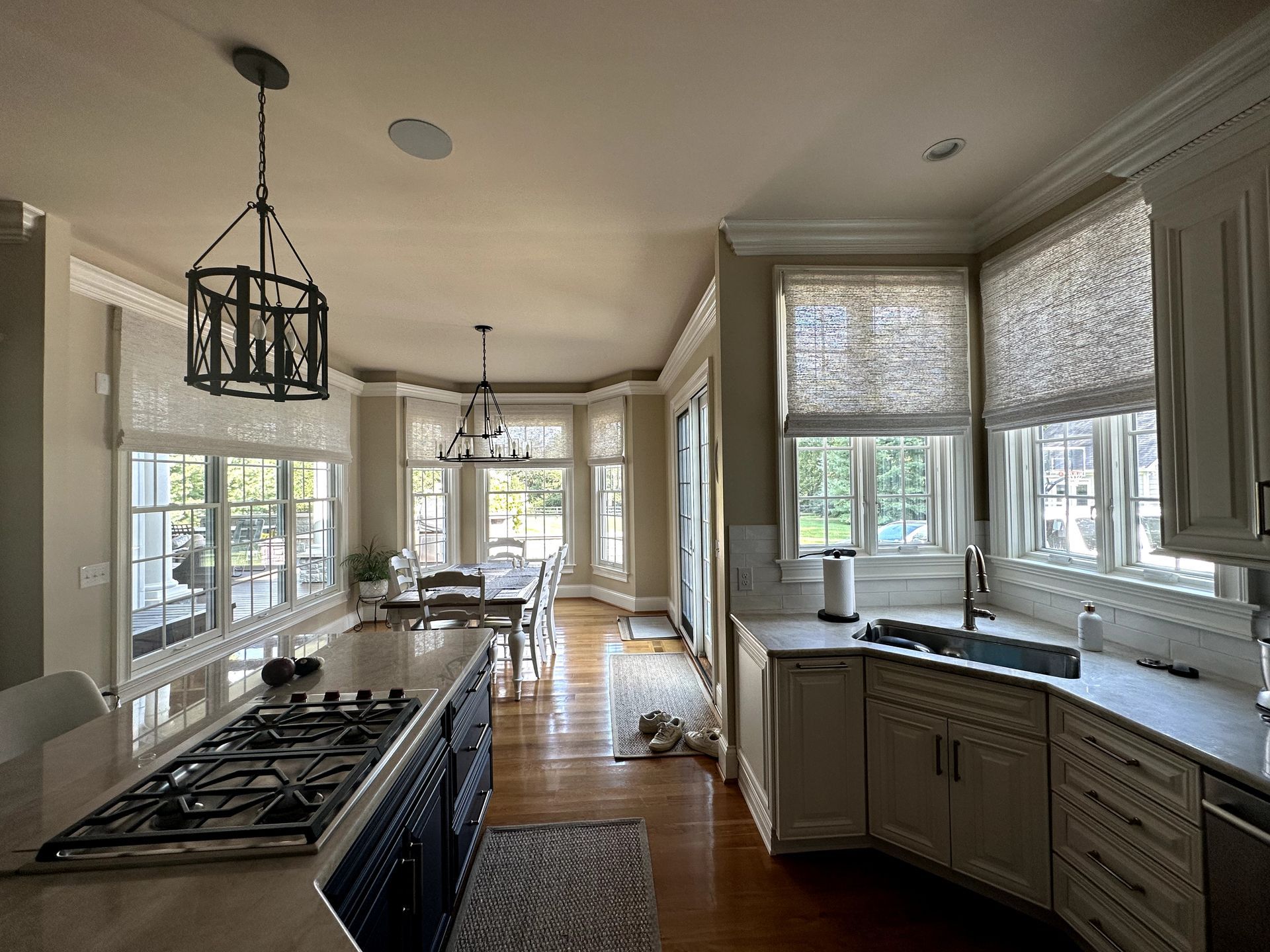 Kitchen with dark blue island, light cabinets, windows, and dining area.