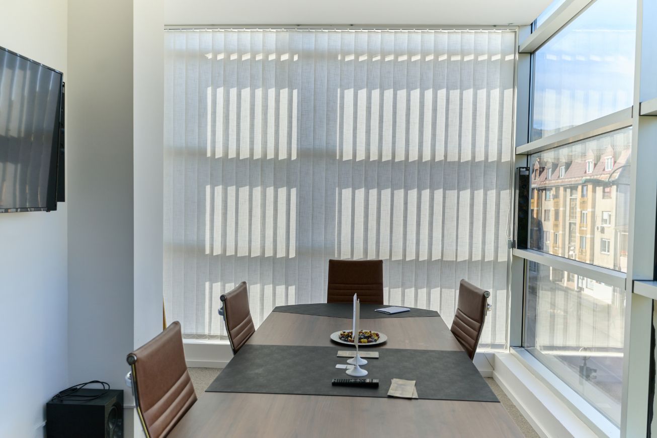 Modern dining room with table, chairs, and window blinds.