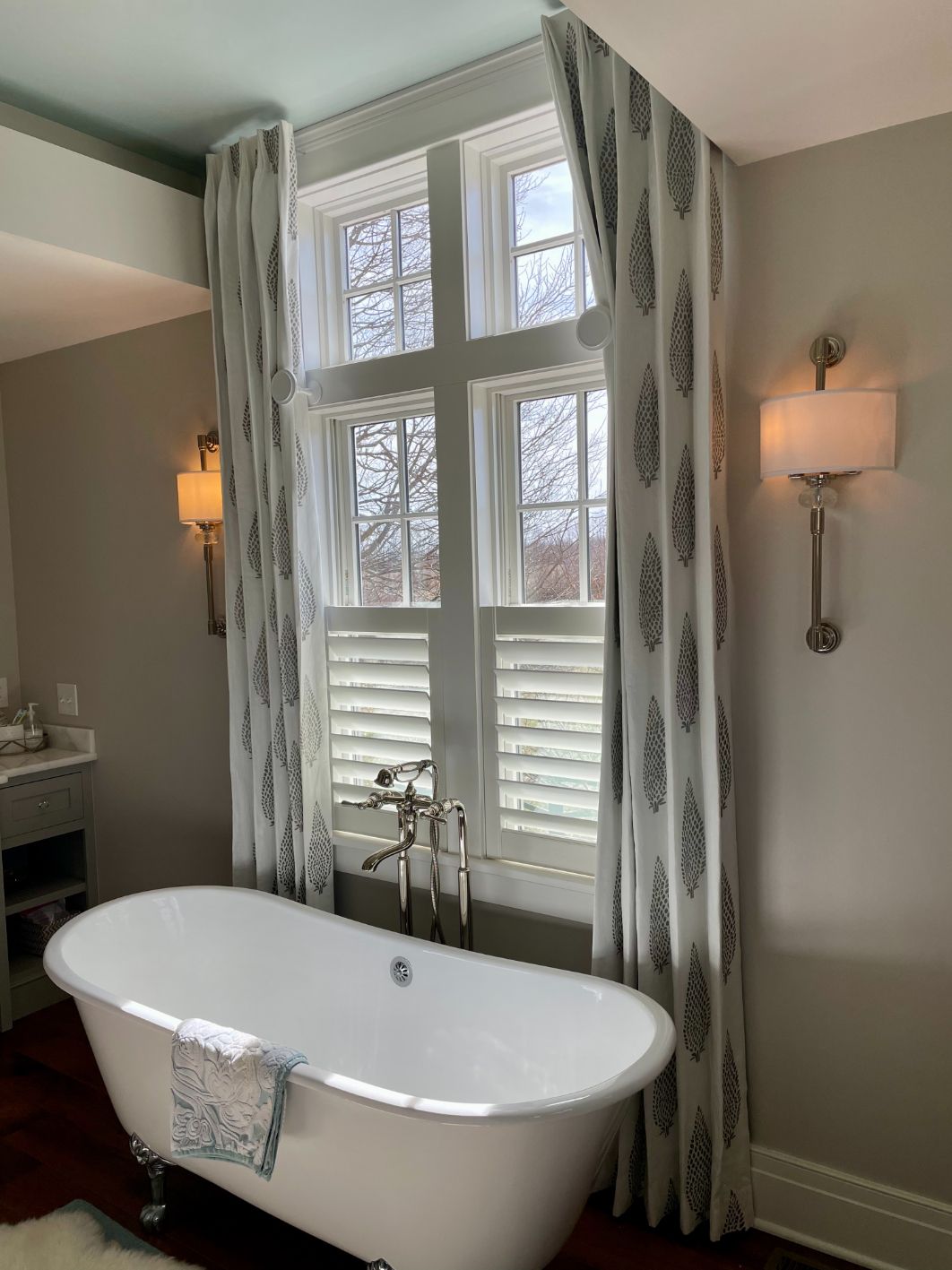 A classic clawfoot tube in a bathroom sits below a window with plantation shutters - window fashions on wheels, ky