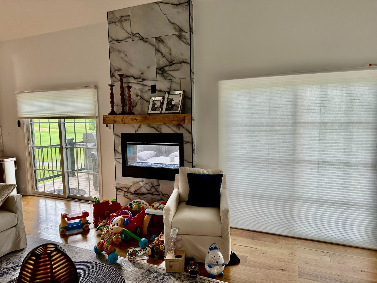 Living room with fireplace, toys on the floor, and a large white window shade covering most of the wall