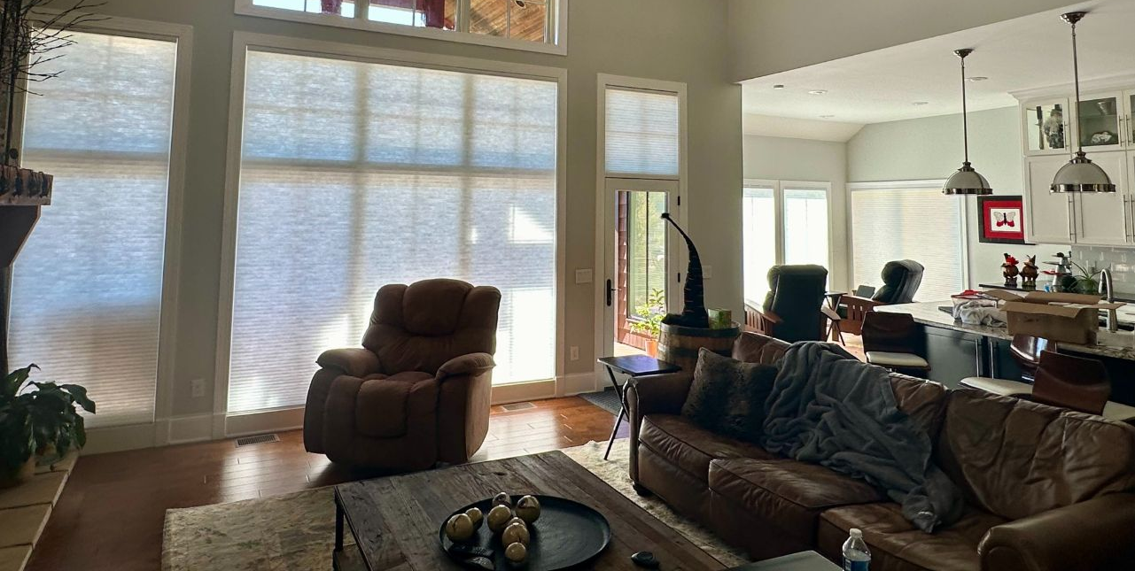 Living room with leather sofa, recliner, large windows, and open kitchen.