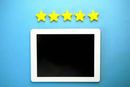 A tablet with a black screen rests on a blue background below a horizontal row of five yellow stars.