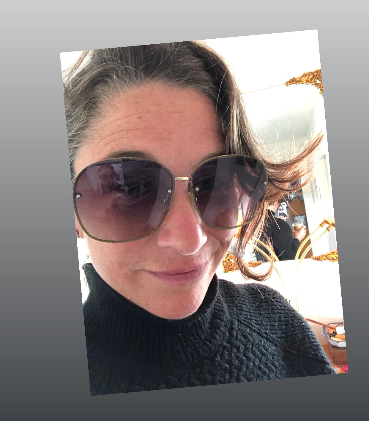 Woman in sunglasses, black sweater, looking at the camera.