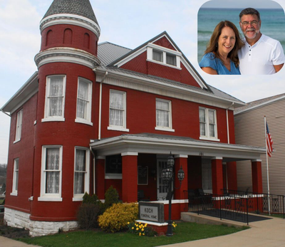 Sunset over a calm lake, reflecting golden light, with grassy foreground and treeline.